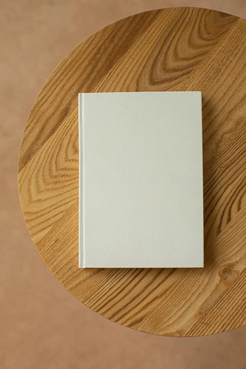 A single book resting on a round wooden table